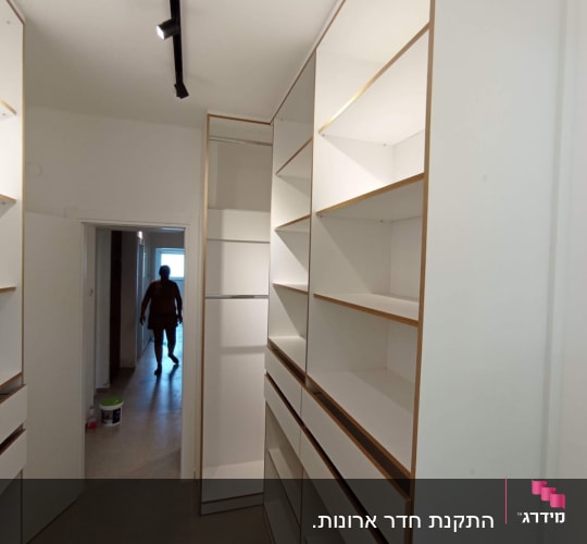 ארונות מדפים לבנים במסדרון צר